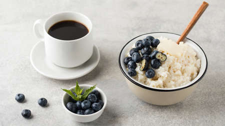 Rice milk porridge with blueberries and a mug of black coffee. Healthy breakfast.の写真素材