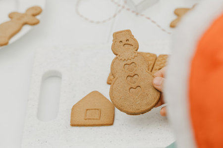 The boy is holding a gingerbread cookie in the shape of a snowman. Cooking Christmas cookies.