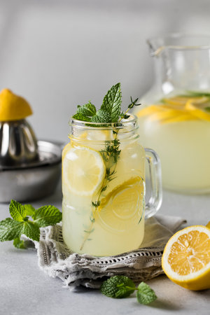 Homemade lemonade with fresh lemon slices and mint leaves in a glass. A summer refreshing drink.