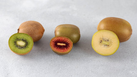 Different varieties of kiwi lie in a pile on the table. Halves of red, yellow and green kiwi.の写真素材