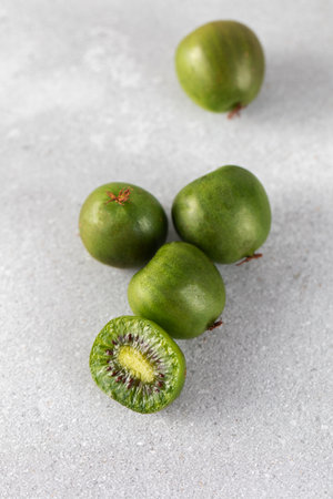 Mini kiwi on a gray table, whole and half. Tropical fruits. Kiwi berry.の写真素材