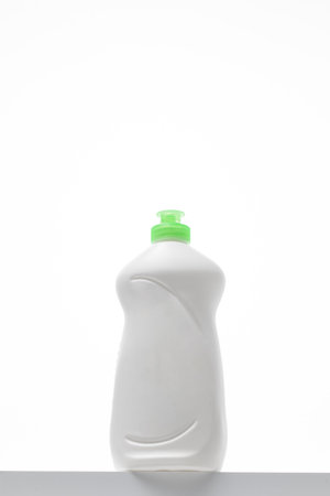 A drop of dishwashing gel flows out of the bottle. The layout is made of white plastic with gel for washing dishes.の写真素材