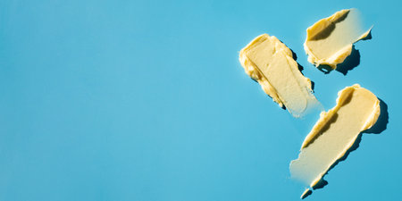 A samples of a yellow cosmetic product on a blue background. Swatch. Skin care. Sunscreenの写真素材