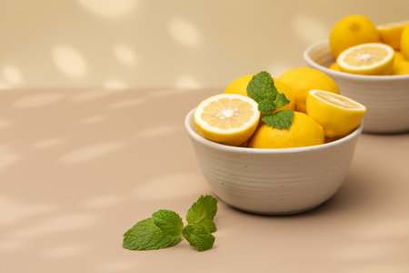 Still life yellow ripe lemons in a ceramic plate with a sprig of mint on the table. Copy spaceの写真素材