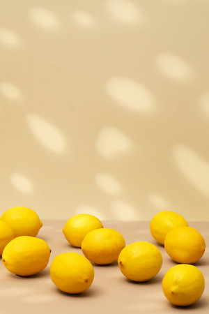A handful of yellow ripe lemons on a beige background with a shadow pattern. Copy spaceの写真素材