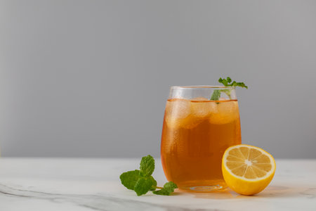 A glass of cold tea, ice cubes, lemon slices and a sprig of mint. Cooling summer drinks.