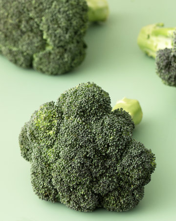 Fresh raw whole broccoli on a green background. Vegetarianism, healthy eating. Copy space