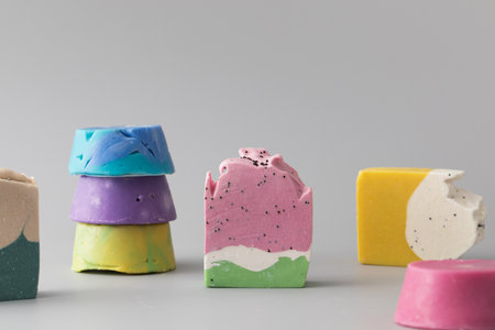 Pieces of different shapes and colors of handmade soap on a gray background. Natural cosmetics.の写真素材