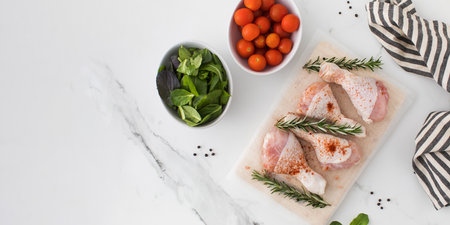 Raw chicken legs with spices and rosemary sprigs on a wooden cutting board. Copy spaceの写真素材