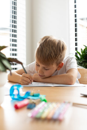 Cute boy doing school homework at home. Distance education. Online education.