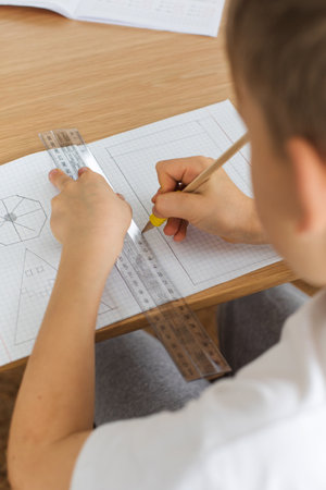 A cute boy makes a drawing with a ruler and pencil. Home lessons. Geometry and drawing.の写真素材