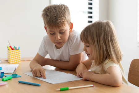 The older brother teaches the younger sister to read letters. Brother and sister, home schooling.の写真素材