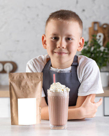 A cute boy made a milkshake. The child is standing at the table with a milkshake and a craft packageの写真素材