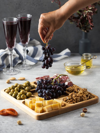 Snacks for wine in a wooden menagerie. Cheese, sausages, berries in a plate, festive serving of...