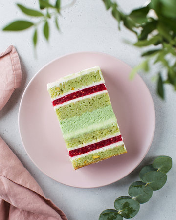 A piece of raspberry and pistachio cake on a pink plate. Bakeryの写真素材