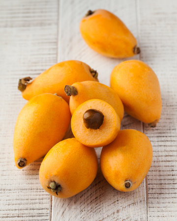 Fruits of ripe juicy medlar on a white wooden background. Medlar whole and in section.の写真素材