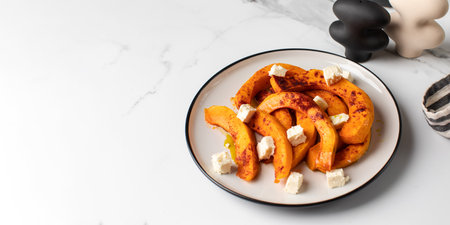 Baked pumpkin slices with spices and cubes of feta cheese. Pumpkin dishes. Copy spaceの写真素材
