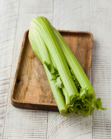 Fresh celery on a wooden board on a white wooden background. Healthy eating.の写真素材