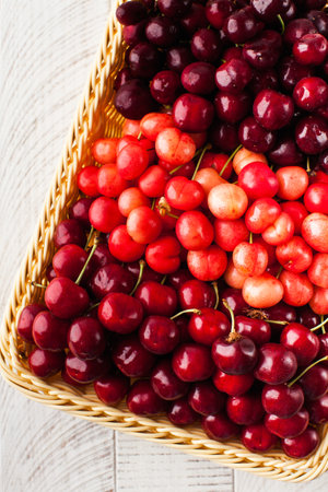 Ripe juicy cherries of different varieties in a wicker basket. Harvesting.の写真素材