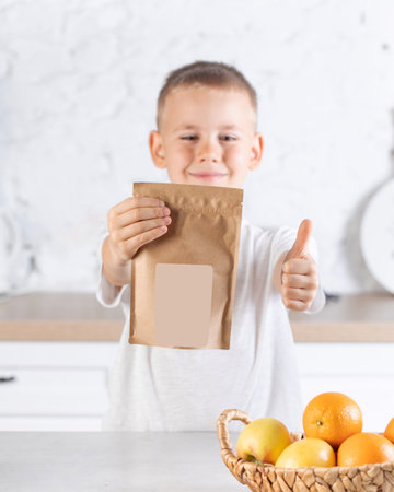 A cute boy stands and holds a craft package with a place for your logo and advertising.の写真素材