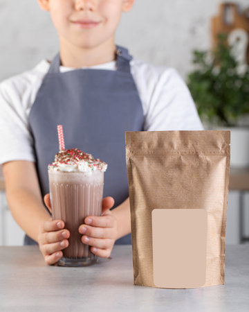 Craft packaging with a place for your logo and a cute boy in the kitchen holding a glass with a chocolate milkshake.の写真素材