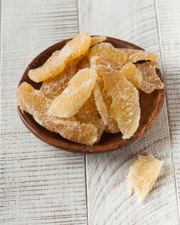 Candied ginger in a plate on a white wooden background. candied fruitsの写真素材