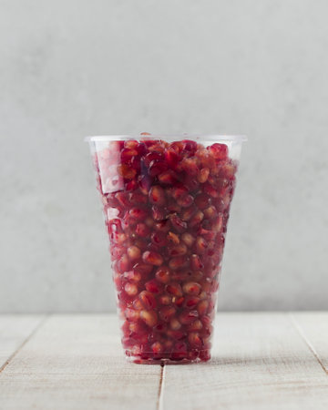 Peeled juicy pomegranate in a transparent plastic cup. Fruit salad in a serving bowl,の写真素材