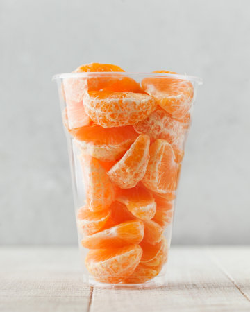 Slices of tangerine in a clear glass. Fruit salad, takeaway food.の写真素材