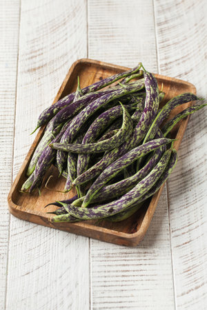 Long spotted stringed raw beans on a wooden background. Vegetables.