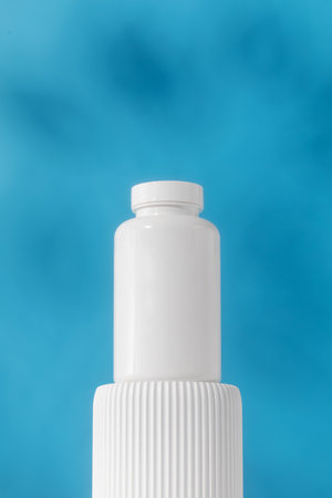 Mockup is a white jar with pills or vitamins on a podium. Medical preparations.の写真素材