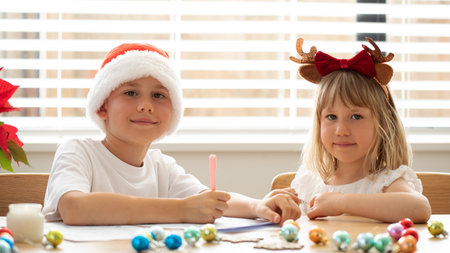 Cute brother and sister in Christmas costumes are writing a letter to Santa Claus. New Years Eveの写真素材