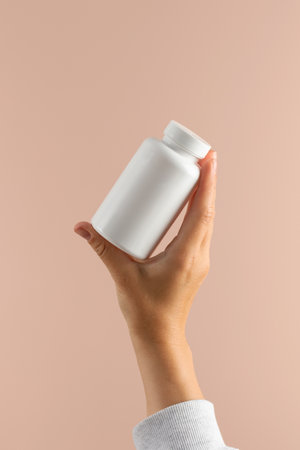 A womans hand holds a white pill jar and in the other hand shows a white pill. Pharmacy, medicinesの写真素材