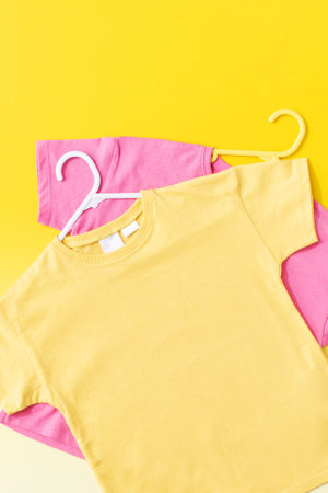 Yellow and pink childrens T-shirts on a yellow background. Flat lay.の写真素材