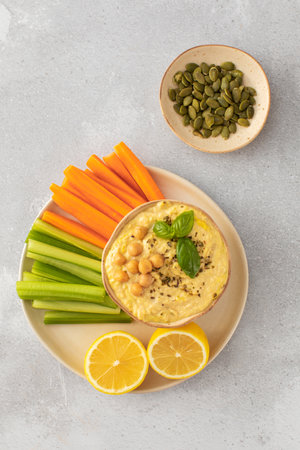 A dish of hummus with a side of carrots, celery and more hummus on a plateの写真素材