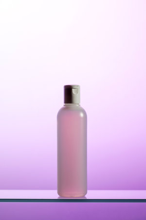A plastic bottle with liquid cosmetics and tonic stands on a glass shelfの写真素材
