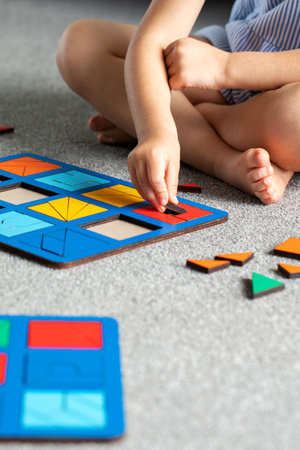 A cute girl is playing a logical wooden game on the floor in the room. Educational toy.の写真素材
