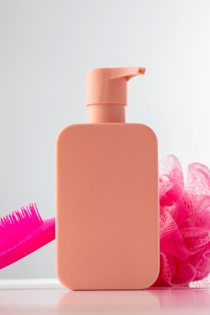 Pink shampoo dispenser with comb and loofah, with copy space. Skin careの写真素材