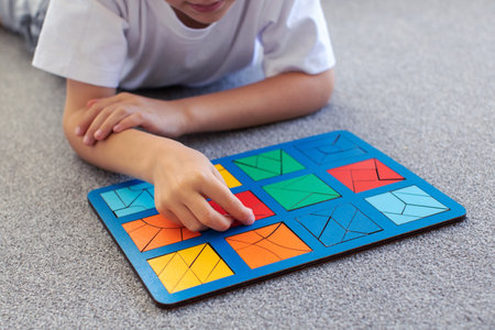 A boy is playing a logical wooden game on the carpet. Montessori educational toys, geometric puzzle