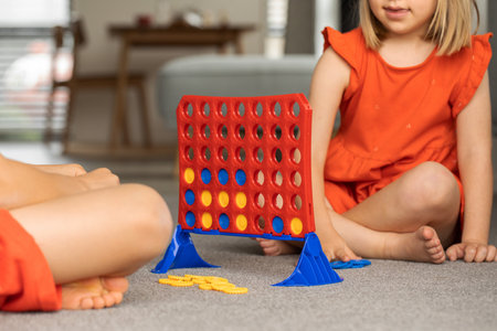 Siblings engrossed in a strategic board game, enhancing their logic. Kids play board games - four in...