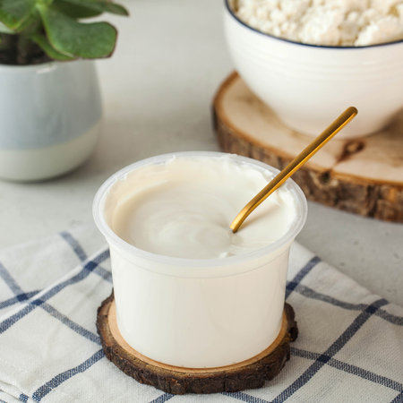 Natural sour cream in a plastic cup made from farm milk. Fermented milk productsの写真素材