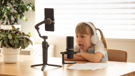 Young girl with headphones smiling during a solo podcast session, equipped with mic and smartphone....
