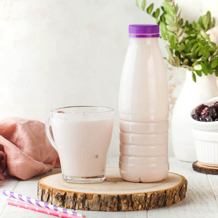 Berry-flavored drinking yogurt served in a glass and a matching bottleの写真素材