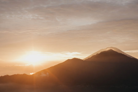 Sunrise over Mount Batur with a golden sky and silhouetted mountains. Travelの写真素材
