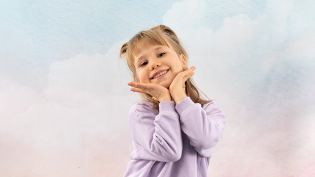 Joyful blonde girl beams with smile putting hands to face