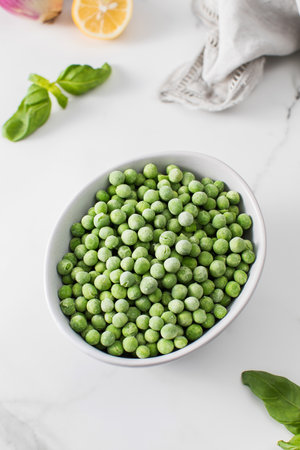 A bowl of frozen green peas on a white background. Fresh and healthy vegetableの写真素材