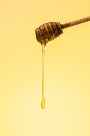 Golden honey dripping from a wooden dipper.