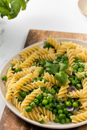 Tasty pasta with green peas and basil on white marble tableの写真素材