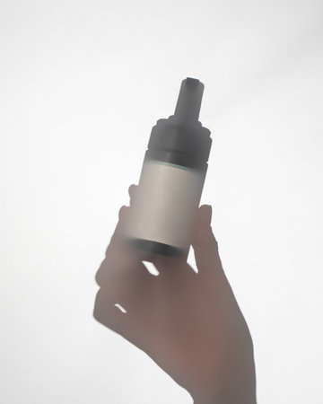 Woman hand silhouette holds dispenser bottle with mockup tagの写真素材