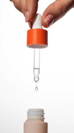 A womans hand holds a pipette and dials skin serum into a glass pipette. skin care.の写真素材