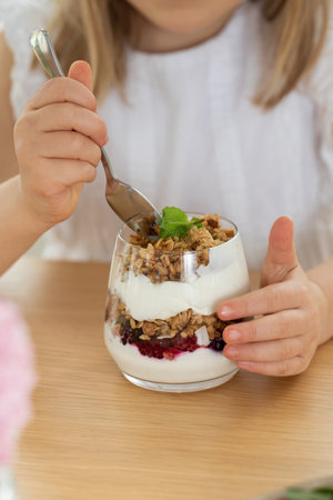 Close up image of a child happily eating a nutritious yogurt parfait with fresh fruit and granolaの写真素材